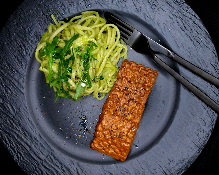 Schwarzer Teller, darauf eine Portion Linguine mit einigen Rucola-Blättern, sowie ein Streifen vom alternativen Lachsfilet.